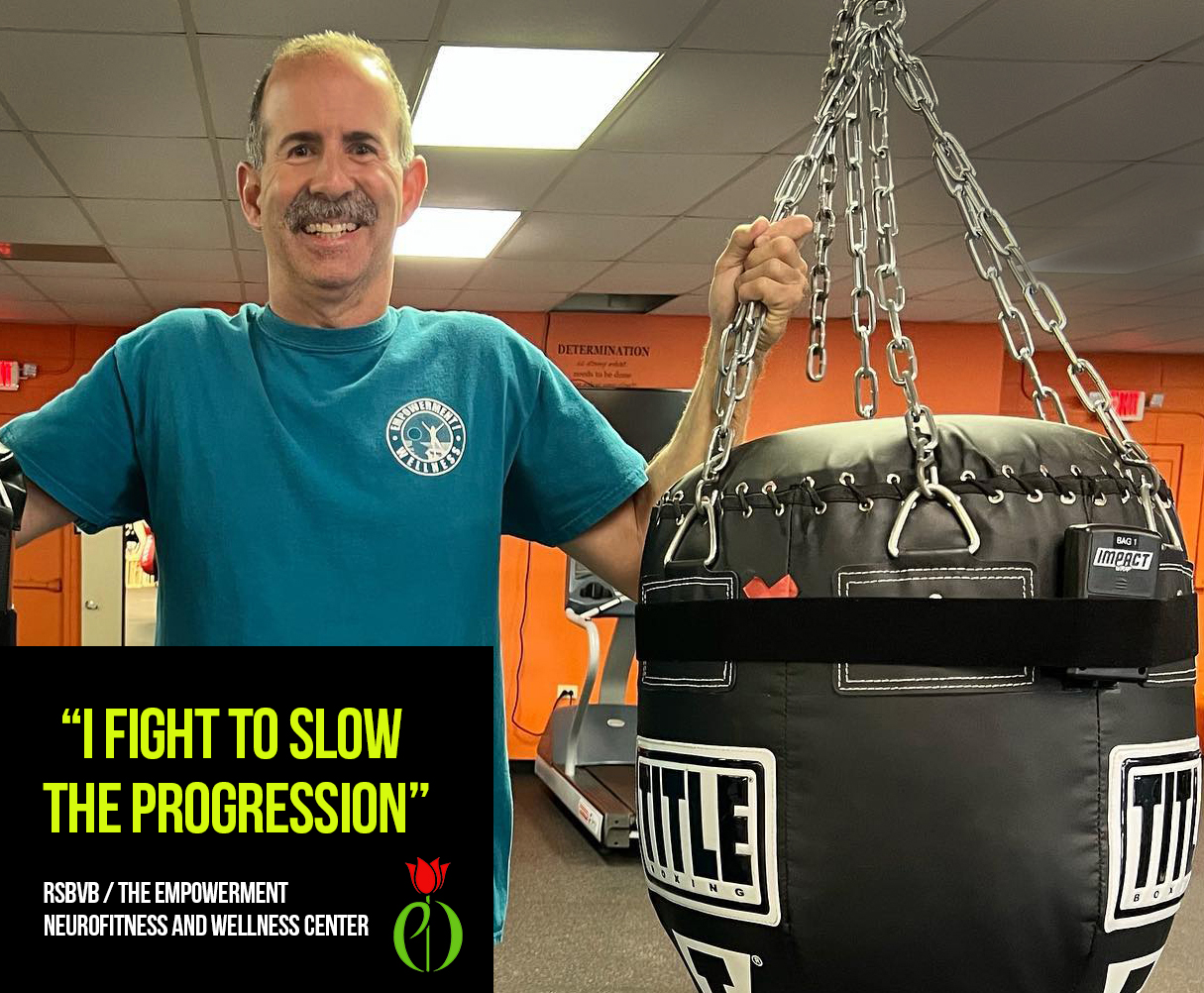 Man with Parkinson's Disease who participates in Rock Steady Boxing stands with a heavy bag fitted with an Impact Wrap sensor.