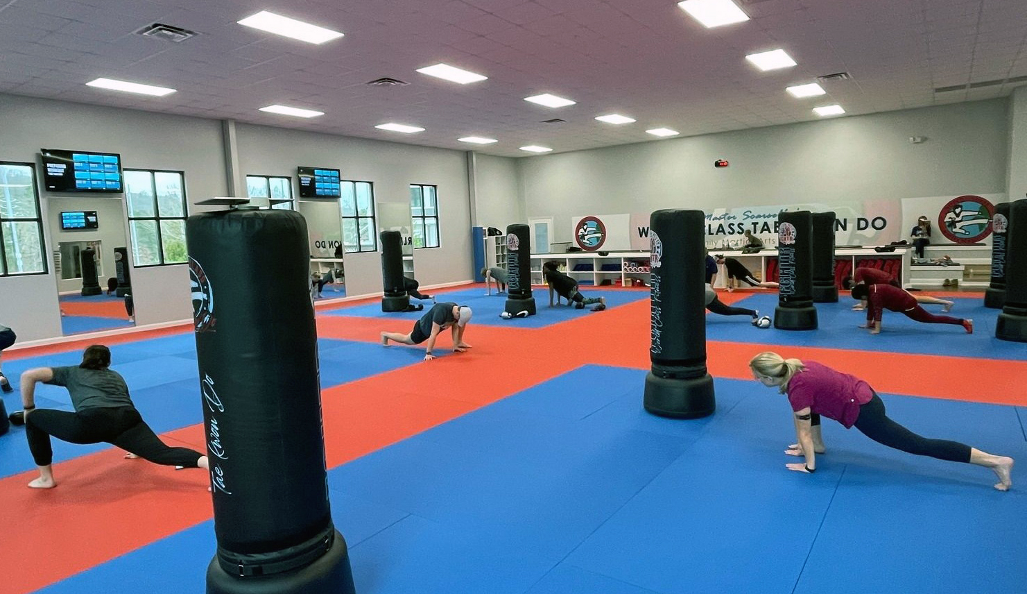 FGHTR Fitness Kickboxing fitness class participants stretching next to heavy bags at Master Scarsella's World Class Tae Kwon Do.