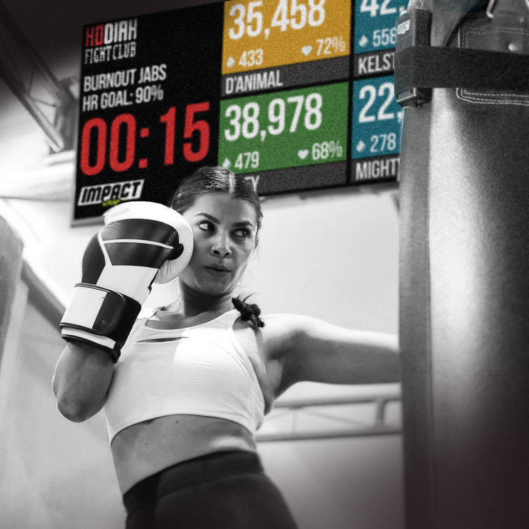 Woman boxing with heavy bag using the Impact Wrap striking workout performance tracking platform integrated with Heart Rate Monitoring and Calorie Burn Count.
